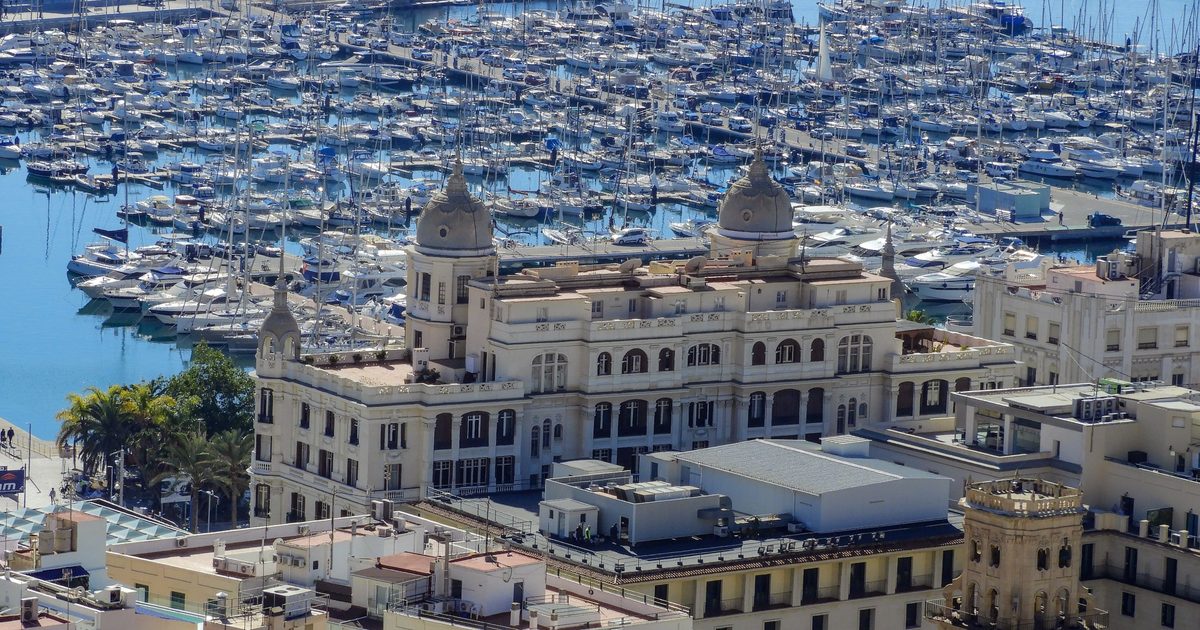 Vista aérea del puerto deportivo de Alicante con un edificio histórico de cúpulas en primer plano