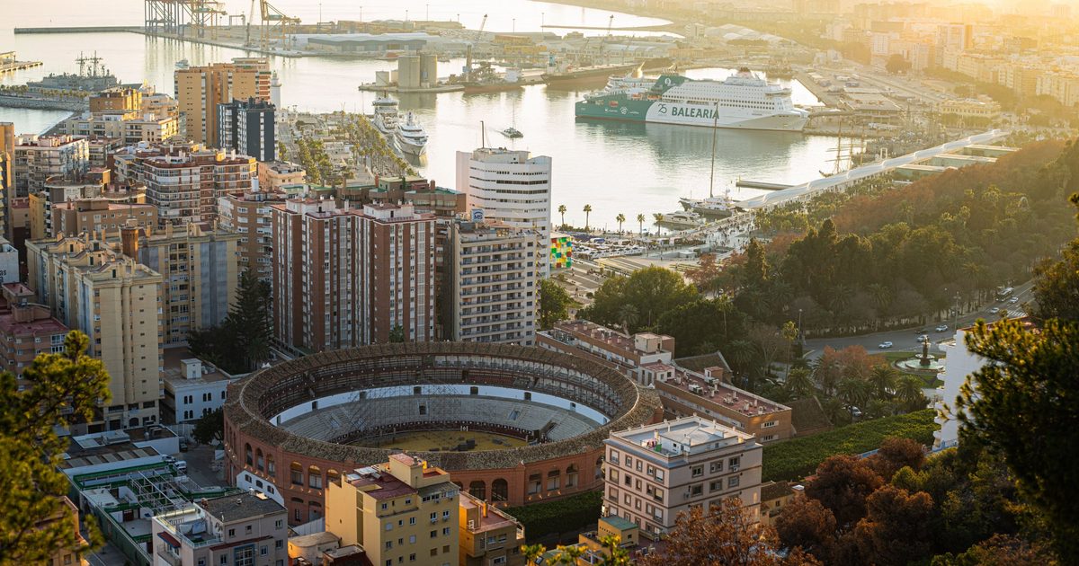 Vista aérea de Málaga al atardecer con la plaza de toros, el puerto y un ferry